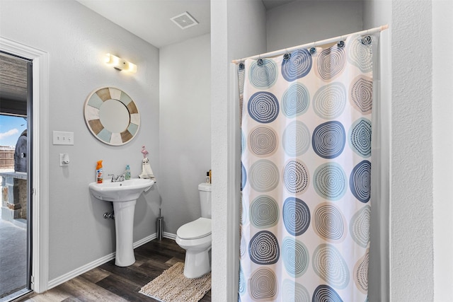 bathroom featuring visible vents, a shower with shower curtain, toilet, a sink, and wood finished floors