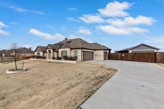 view of front of property with concrete driveway, brick siding, an attached garage, and fence