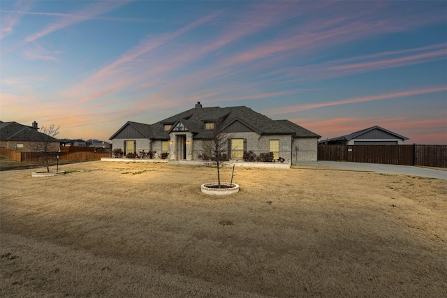 view of front of home featuring stone siding, fence, and a lawn