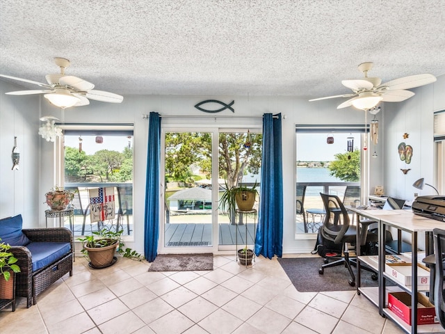 interior space featuring ceiling fan, a textured ceiling, a water view, and light tile patterned flooring