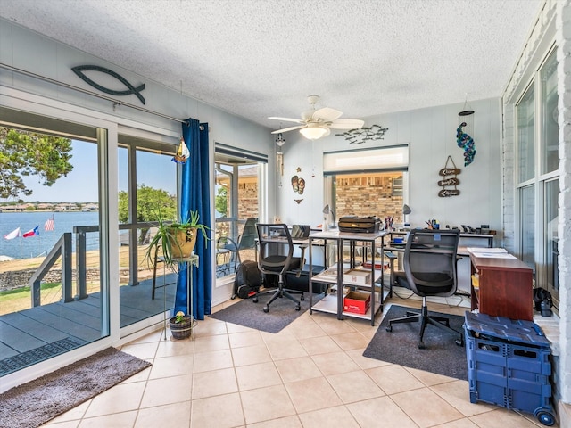 tiled office with a textured ceiling, a healthy amount of sunlight, a water view, and ceiling fan