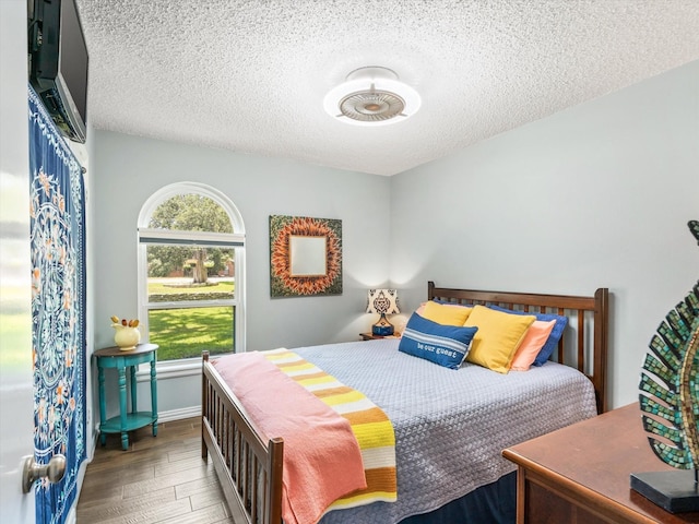 bedroom with a textured ceiling and dark hardwood / wood-style floors