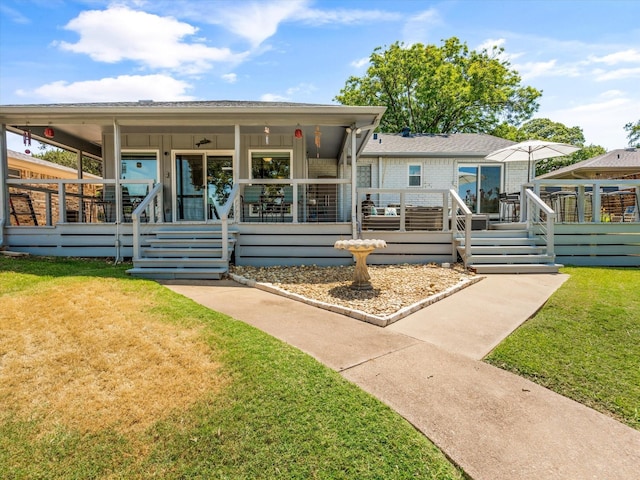 rear view of property featuring covered porch and a lawn