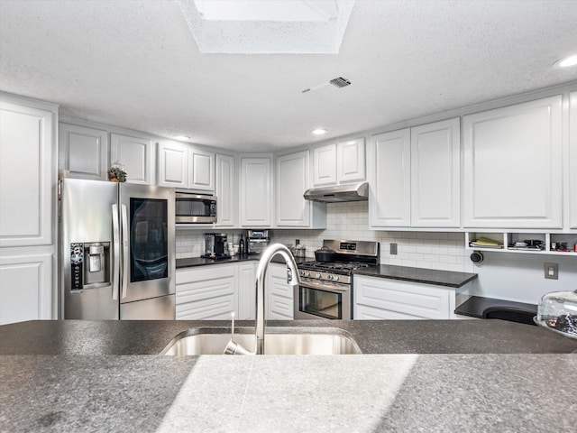 kitchen featuring decorative backsplash, a textured ceiling, white cabinets, and stainless steel appliances