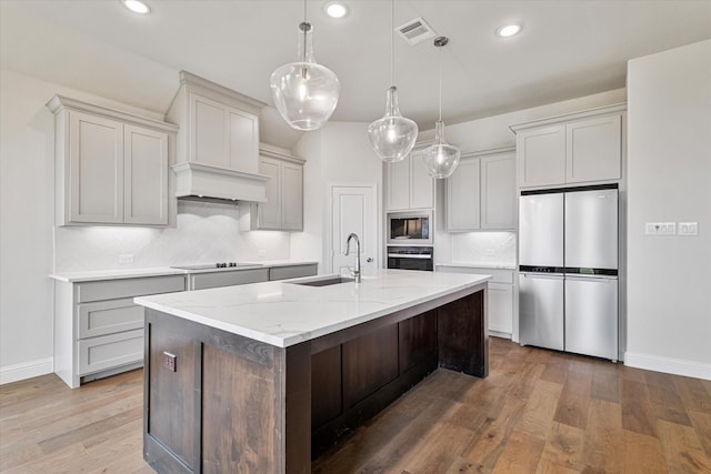 kitchen featuring light stone countertops, sink, wall oven, stainless steel refrigerator, and built in microwave