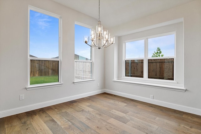 unfurnished dining area featuring light wood-type flooring and an inviting chandelier