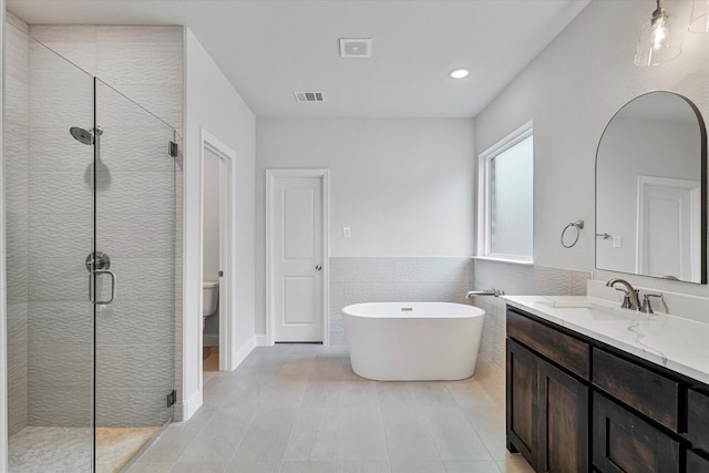 full bathroom with independent shower and bath, toilet, tile walls, and vanity