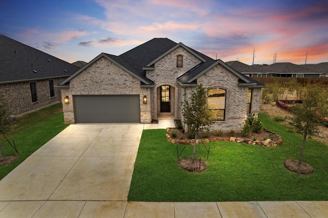 french country style house featuring a garage and a lawn