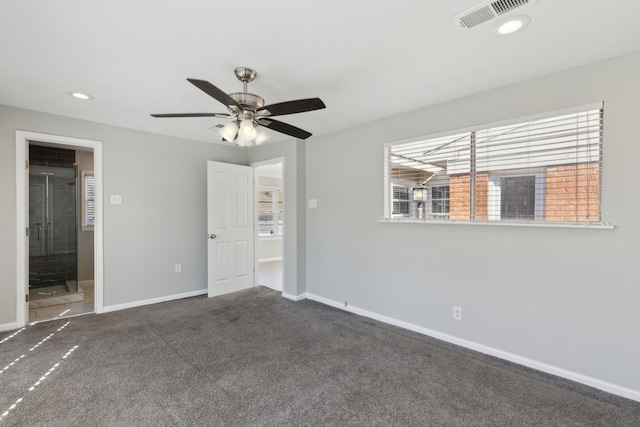 unfurnished room with ceiling fan and dark carpet