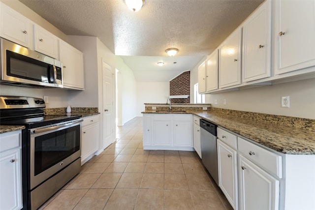 kitchen with white cabinets, stainless steel appliances, kitchen peninsula, and a textured ceiling