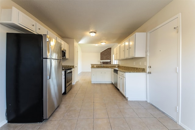 kitchen featuring stainless steel appliances, white cabinetry, dark stone counters, and light tile patterned floors