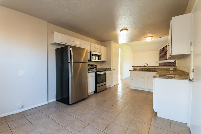 kitchen with appliances with stainless steel finishes, a textured ceiling, light tile patterned floors, white cabinets, and kitchen peninsula