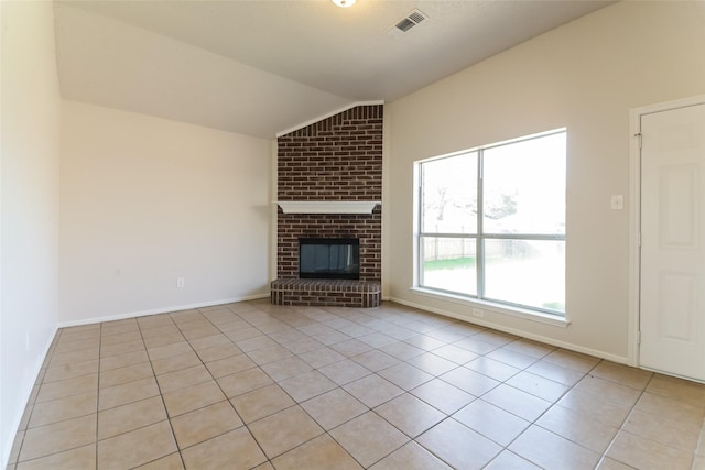 unfurnished living room featuring a brick fireplace, light tile patterned floors, and lofted ceiling