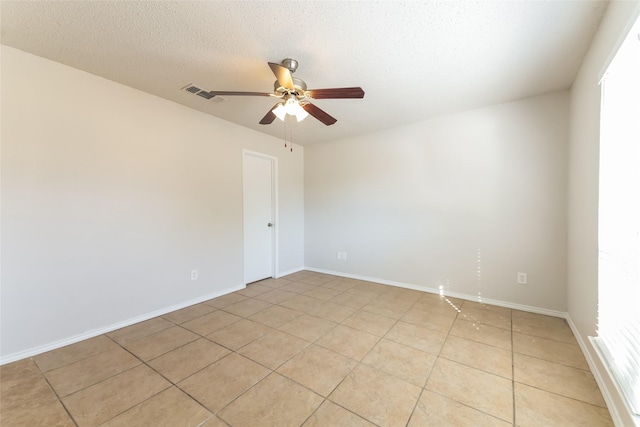 empty room with a textured ceiling, light tile patterned floors, and ceiling fan