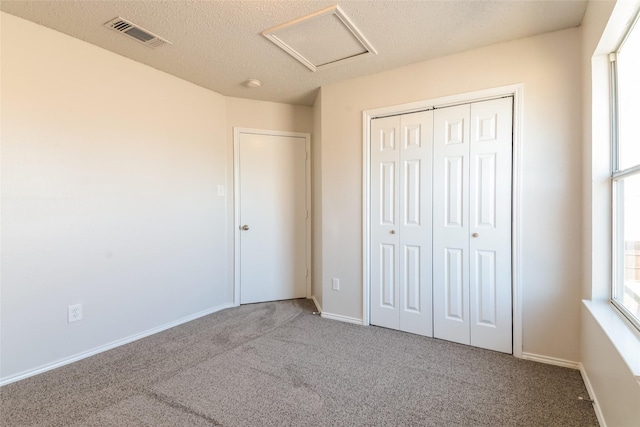 unfurnished bedroom featuring a textured ceiling, a closet, and carpet flooring