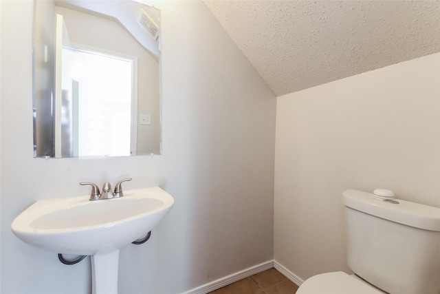 bathroom with tile patterned floors, a textured ceiling, toilet, and lofted ceiling