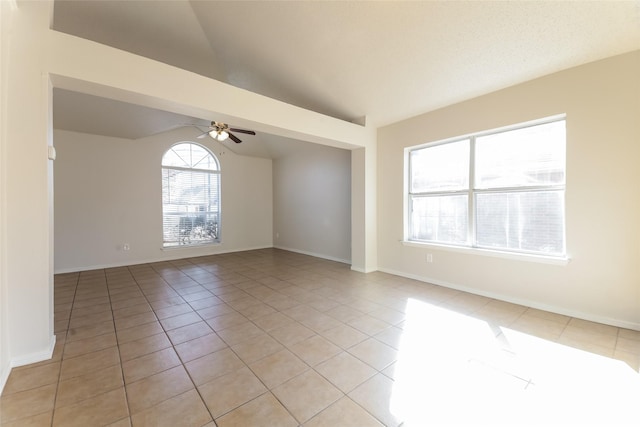 spare room featuring ceiling fan, light tile patterned floors, and vaulted ceiling