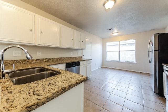 kitchen with sink, white cabinets, light tile patterned floors, a textured ceiling, and stainless steel appliances