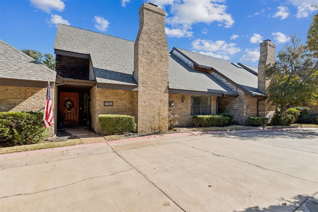 view of front of house with a shingled roof and a chimney