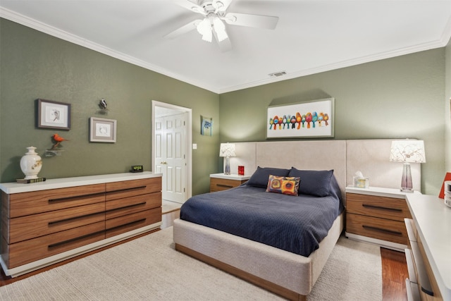 bedroom featuring ceiling fan, ornamental molding, wood finished floors, and visible vents