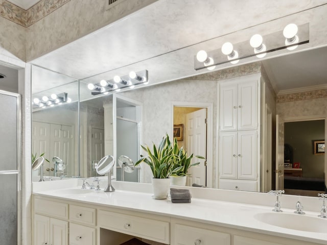 ensuite bathroom featuring crown molding, a stall shower, a sink, and double vanity