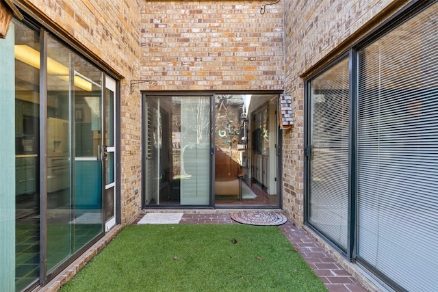 property entrance featuring brick siding and a lawn