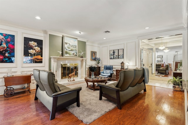 living room featuring wood-type flooring, a high end fireplace, and crown molding