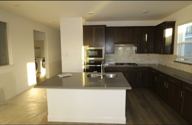 kitchen with tasteful backsplash, sink, stainless steel appliances, and an island with sink