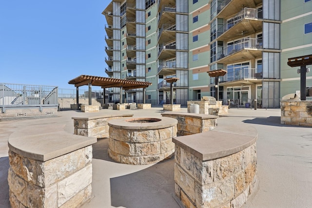 surrounding community with an outdoor fire pit and a pergola