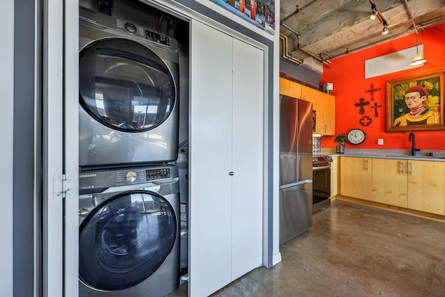 washroom featuring sink, rail lighting, and stacked washer and clothes dryer