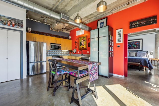 kitchen with decorative light fixtures, decorative backsplash, appliances with stainless steel finishes, and a towering ceiling