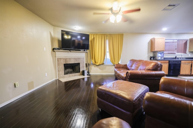 living room with sink, ceiling fan, dark hardwood / wood-style flooring, and a tiled fireplace