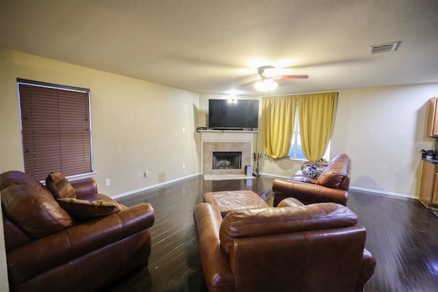 living room with a fireplace, dark wood-type flooring, and ceiling fan