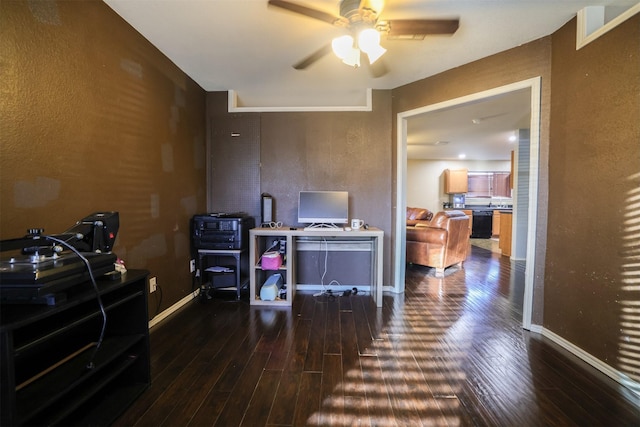 home office with dark wood-type flooring and ceiling fan