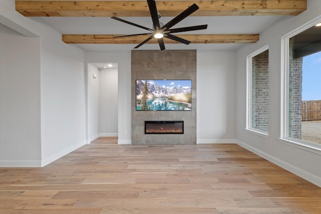 unfurnished living room with a fireplace, light hardwood / wood-style floors, beamed ceiling, and ceiling fan