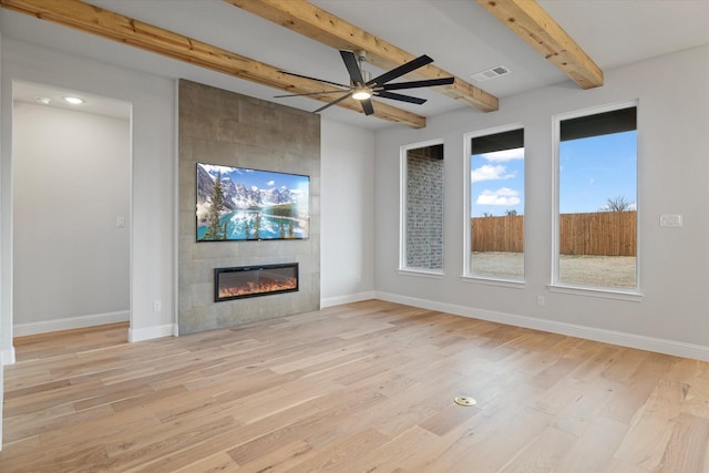 unfurnished living room featuring a tile fireplace, light hardwood / wood-style flooring, beam ceiling, and ceiling fan