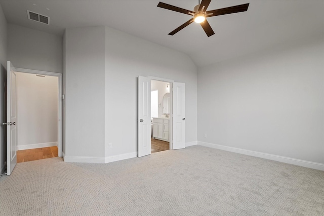 unfurnished bedroom with ceiling fan, connected bathroom, lofted ceiling, and light carpet