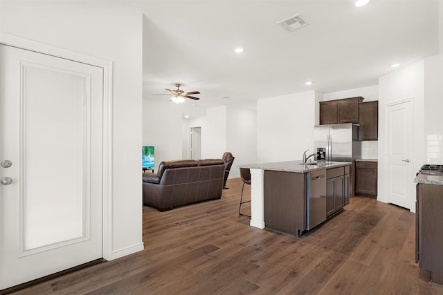 kitchen with dark hardwood / wood-style floors, tasteful backsplash, dishwasher, a kitchen island with sink, and a breakfast bar area