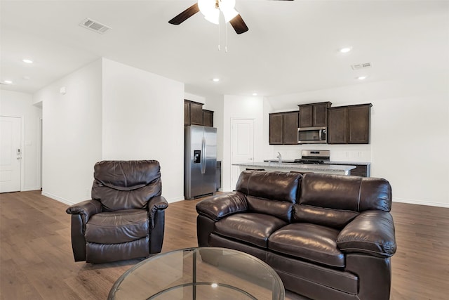 living room with wood-type flooring, sink, and ceiling fan