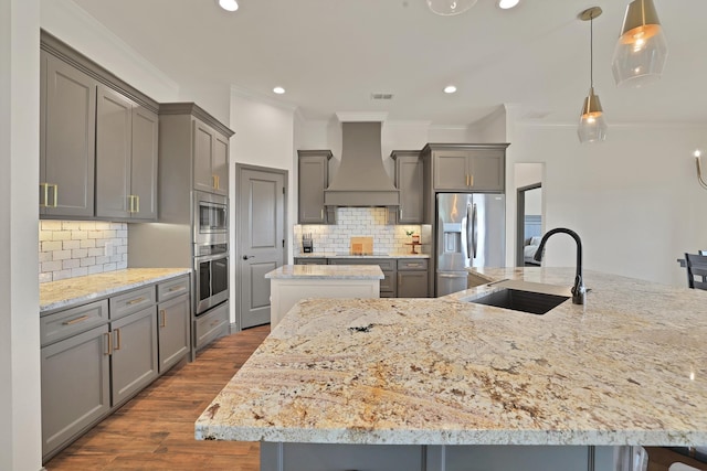 kitchen with a large island, decorative light fixtures, sink, custom range hood, and stainless steel appliances