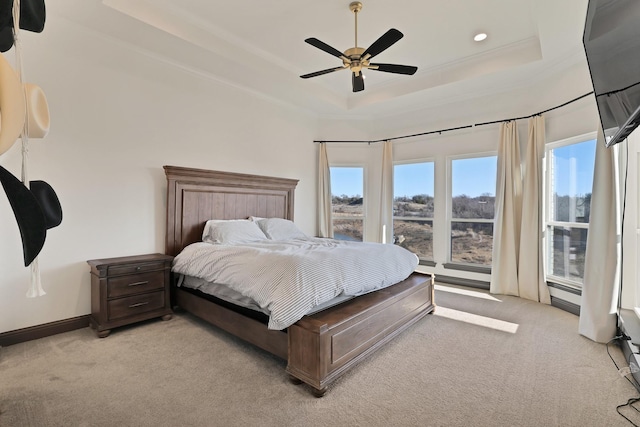 carpeted bedroom featuring ceiling fan and a tray ceiling