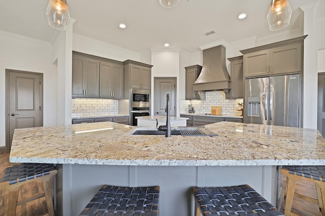 kitchen featuring a kitchen breakfast bar, decorative backsplash, custom range hood, and appliances with stainless steel finishes