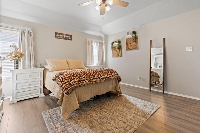 bedroom with ceiling fan, a raised ceiling, and hardwood / wood-style flooring