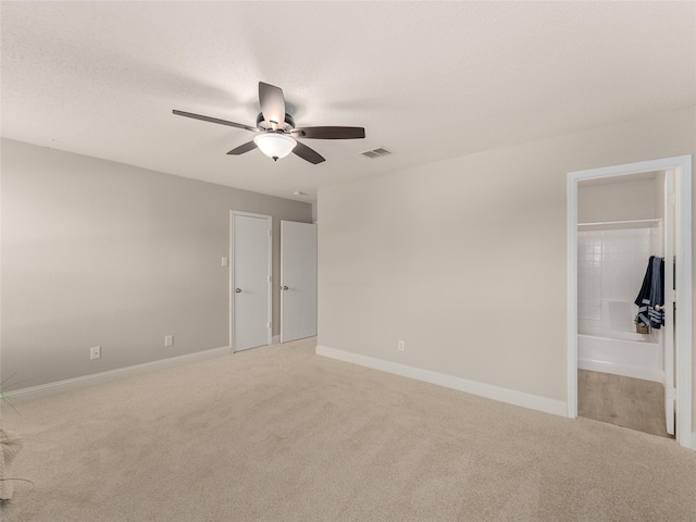 unfurnished bedroom featuring light carpet, ensuite bath, and ceiling fan