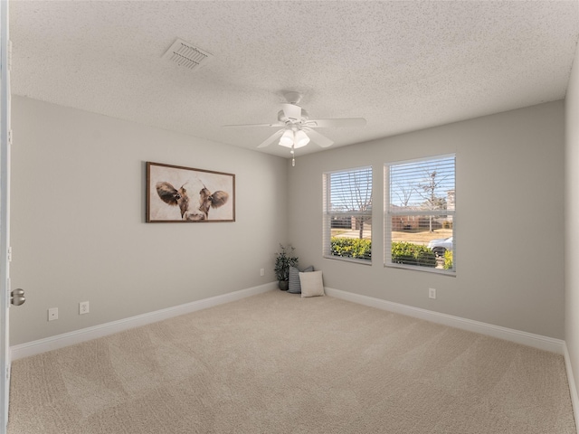 spare room with ceiling fan, a textured ceiling, and light carpet