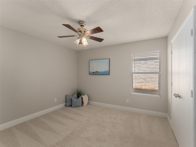 carpeted spare room featuring ceiling fan and a textured ceiling