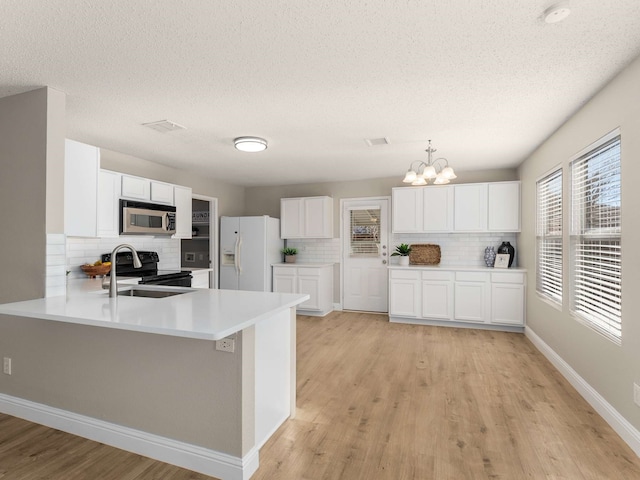 kitchen featuring white fridge with ice dispenser, white cabinets, decorative light fixtures, kitchen peninsula, and black electric range