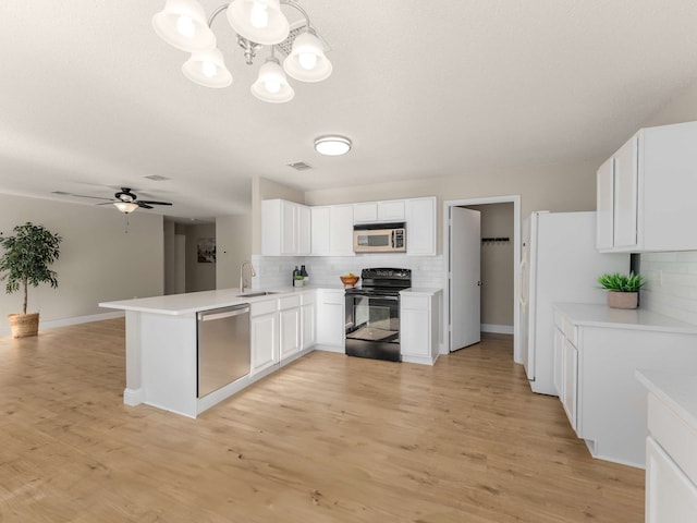 kitchen with kitchen peninsula, tasteful backsplash, white cabinetry, and stainless steel appliances