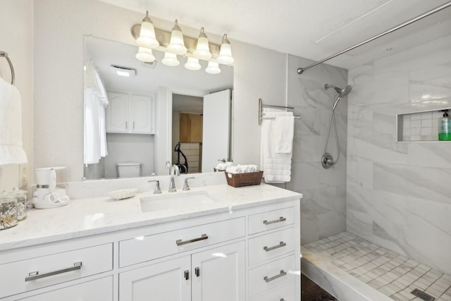 bathroom featuring tiled shower, toilet, and vanity