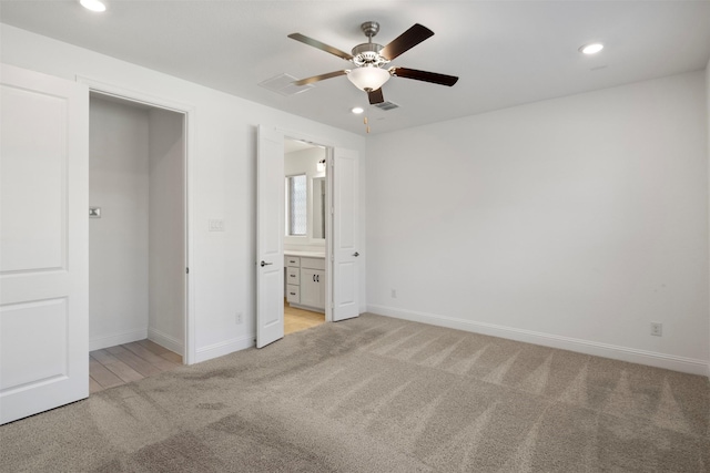 unfurnished bedroom with connected bathroom, light carpet, and ceiling fan